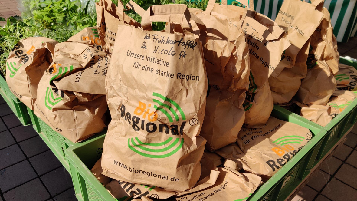 Braune Papiertüten mit Frühkartoffeln am Wochenmarkt in Neuburg