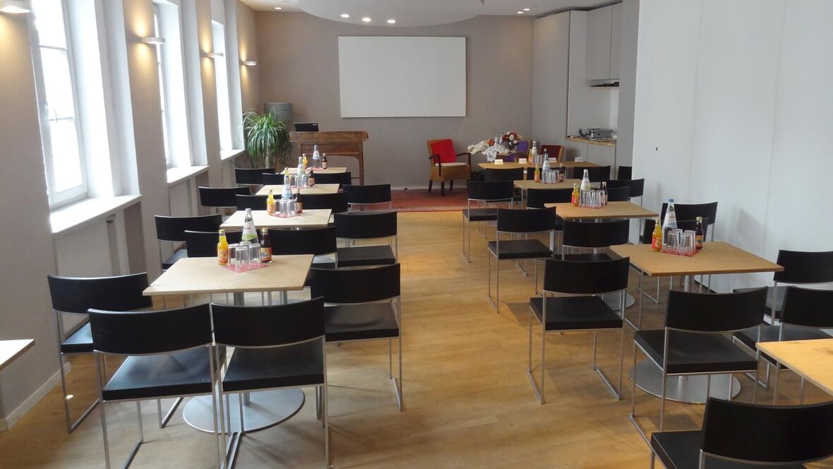 aussicht-sitzungsraum-mit-tischen-stuehlen-und-leinwand