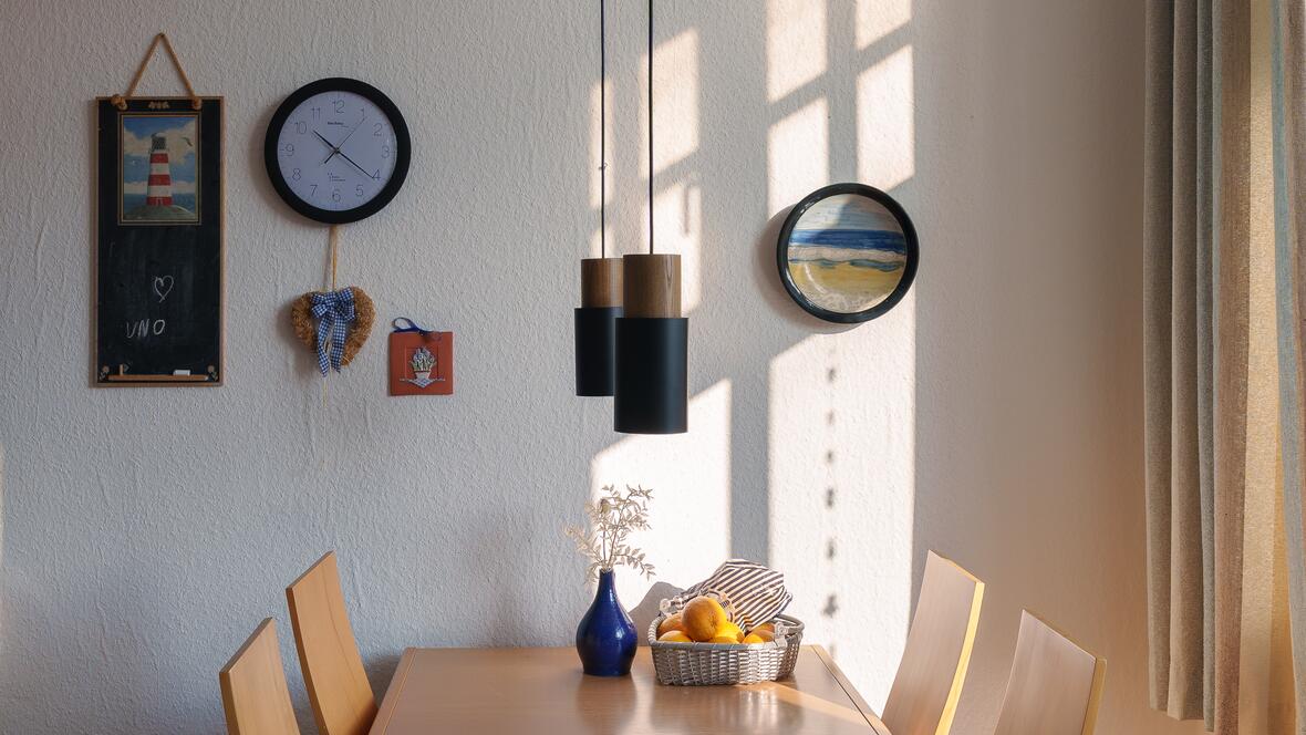 Der Essbereich der Ferienwohnung Charlotte schafft mit Holztisch, hellen Wänden und natürlichem Licht eine angenehme Atmosphäre für Frühstück, Abendessen und entspannte Urlaubstage auf der Nordsee Insel.