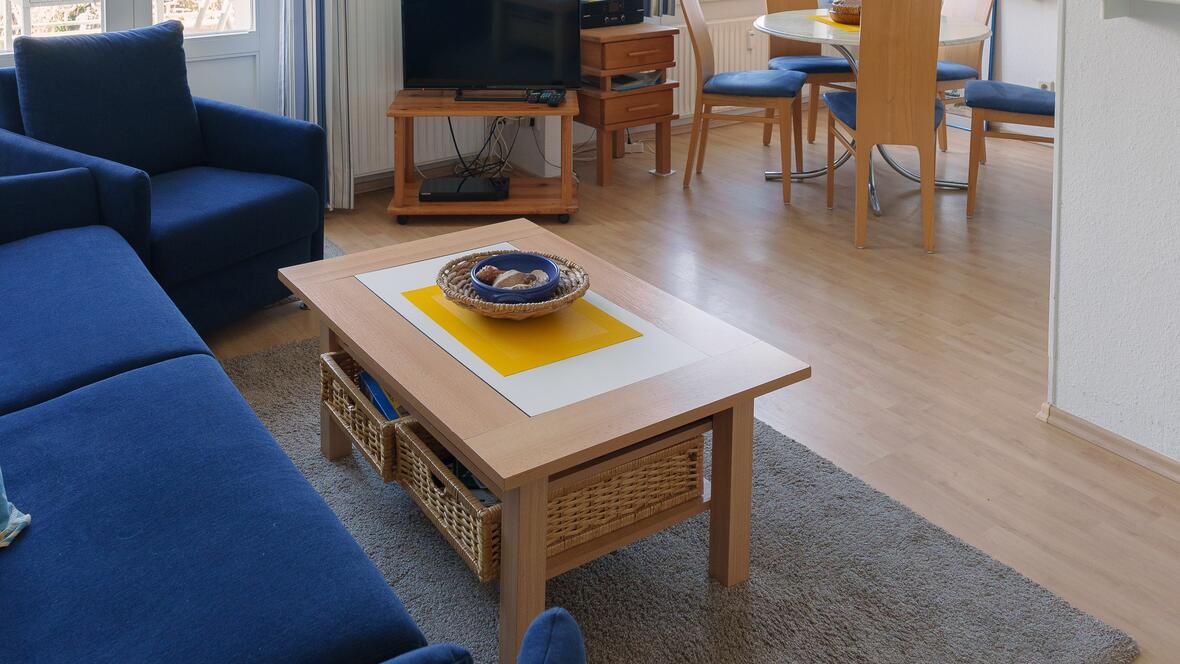 Der helle Wohnbereich der Ferienwohnung Johannes auf Borkum verbindet gemütliche Sitzecke, Essplatz und maritime Einrichtung zu einer einladenden Unterkunft auf Borkum.